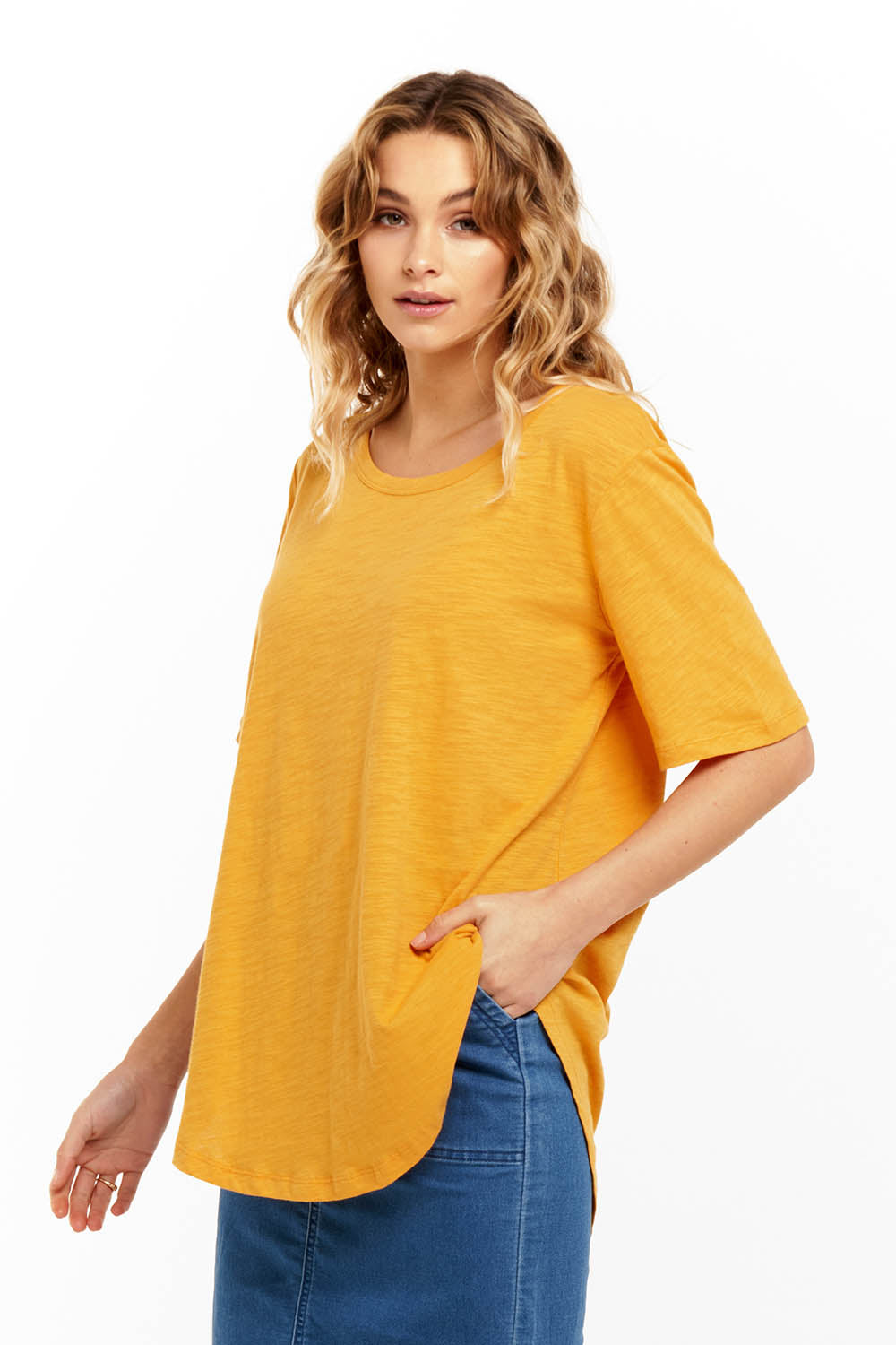 A model wearing the Ariana Tee in colour Mustard, from the front, cropped image