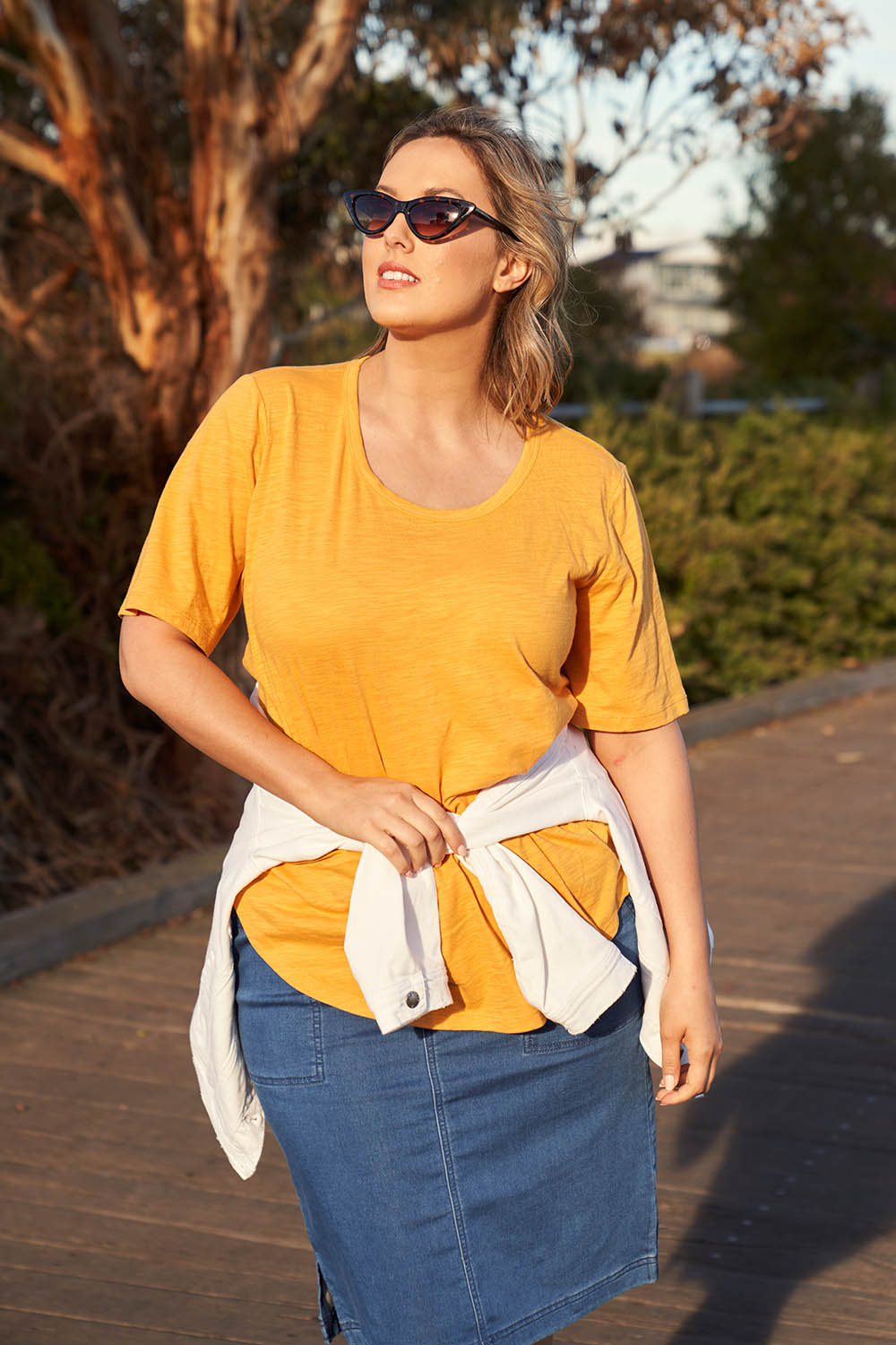 A model wearing the Ariana Tee in colour Mustard, from the front, showing the whole outfit