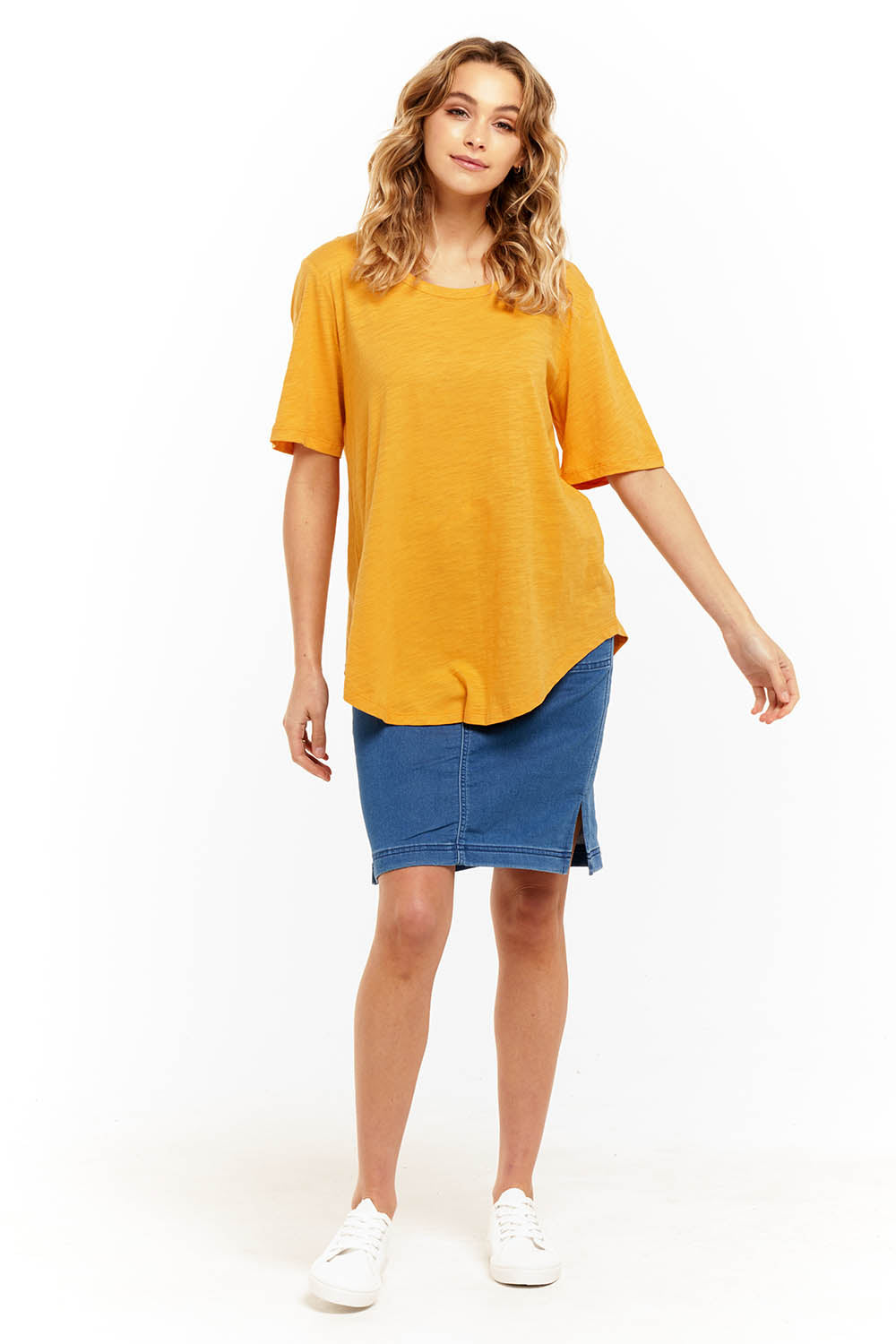 A model wearing the Ariana Tee in colour Mustard, from the front, showing the whole outfit