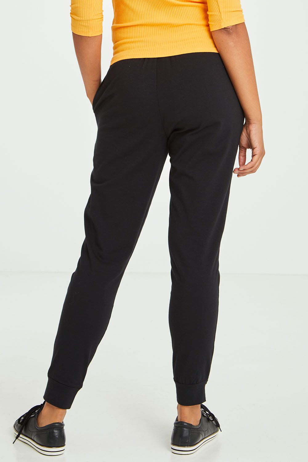 Model Olivia wearing size 10 of the Heidi Pant in colour Black (Black), from the back