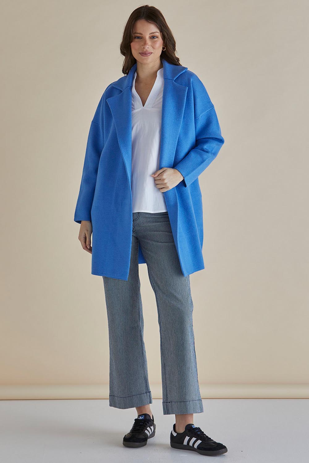 A model wearing the Bristol Coatigan in colour Blue (Blue), from the front, showing the whole outfit