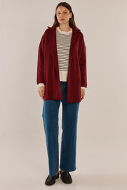 A model wearing the Bristol Coatigan in colour Burgandy (Red), from the front, showing the whole outfit