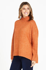 A model wearing the Luna Knit Jumper in colour Amber, from the front, cropped image