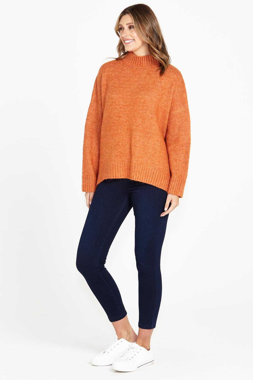 A model wearing the Luna Knit Jumper in colour Amber, from the front, showing the whole outfit
