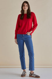 A model wearing the Colette Sweater in colour Red (Red), from the front, showing the whole outfit