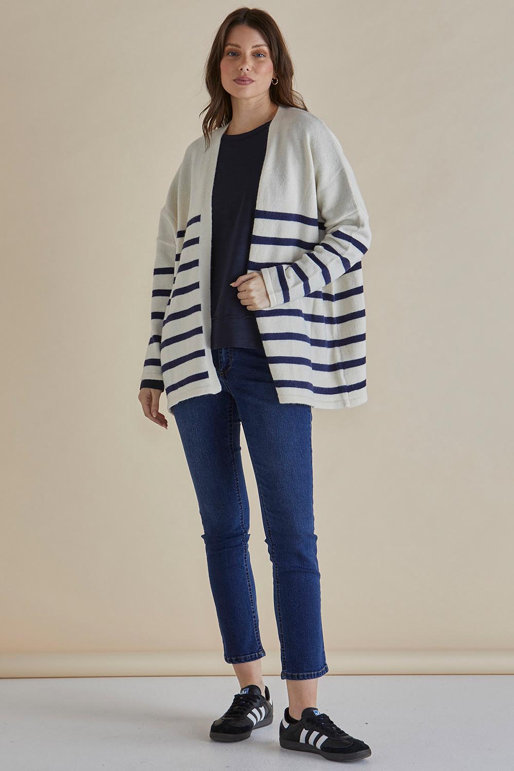 A model wearing the Emy Cardigan in colour Bluestripe (Blue), from the front, showing the whole outfit
