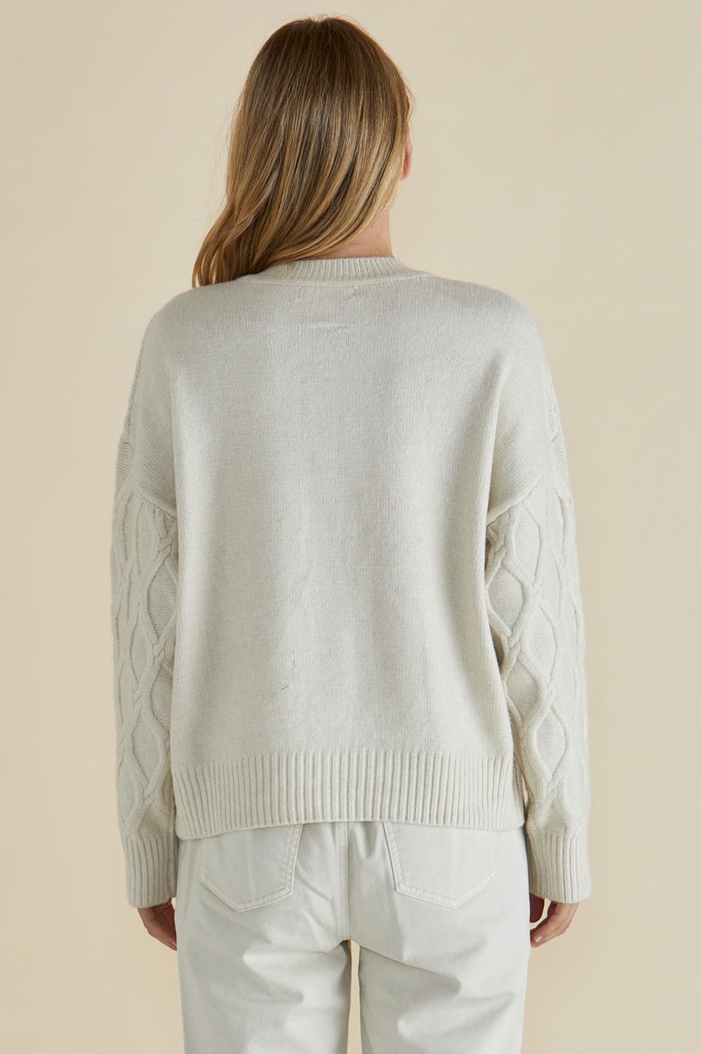 A model wearing the Celene Knit Cardigan in colour Cream, from the back
