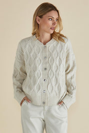 A model wearing the Celene Knit Cardigan in colour Cream, from the front, cropped image