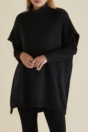 A model wearing the Paige Cotton Blend Poncho in colour Black (Black), from the front, cropped image