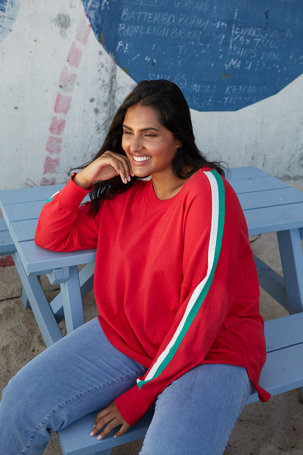 A model wearing the Amelia Knit in colour Raspberry (Red), from the front, showing the whole outfit