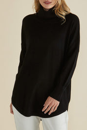A model wearing the Fleur Roll Neck Jumper in colour Black (Black), from the front, cropped image