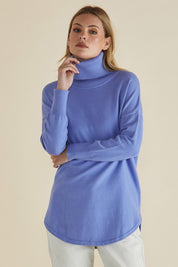 A model wearing the Fleur Roll Neck Jumper in colour Powderblue (Blue), from the front, cropped image