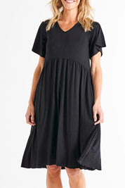 A model wearing the Donna Dress in colour Black (Black), from the front, cropped image