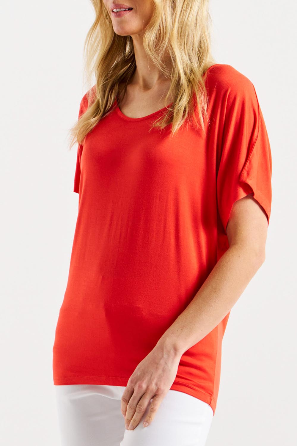 A model wearing the Maui Tee in colour Flamered (Red), from the front, cropped image