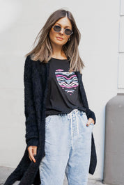 A model wearing the Maui Tee in colour Amore (Black), from the front, showing the whole outfit