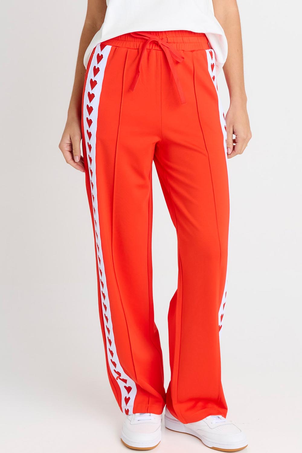 Model Genericm wearing size sample of the Jamie Track Pant – Tomato in colour Tomato, in a cropped view