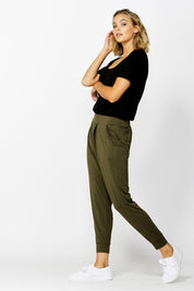 A model wearing the Darwin Pant in colour Olive (Green), from the front, showing the whole outfit