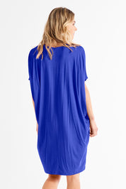 A model wearing the Maui Dress in colour Vividblue (Blue), from the front, showing the whole outfit