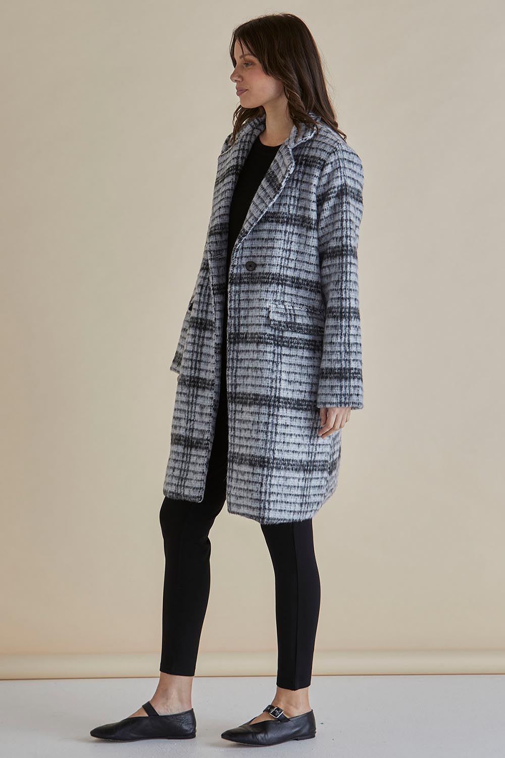 A model wearing the Wanda Coat in colour Monochrome (Grey), from the front, showing the whole outfit