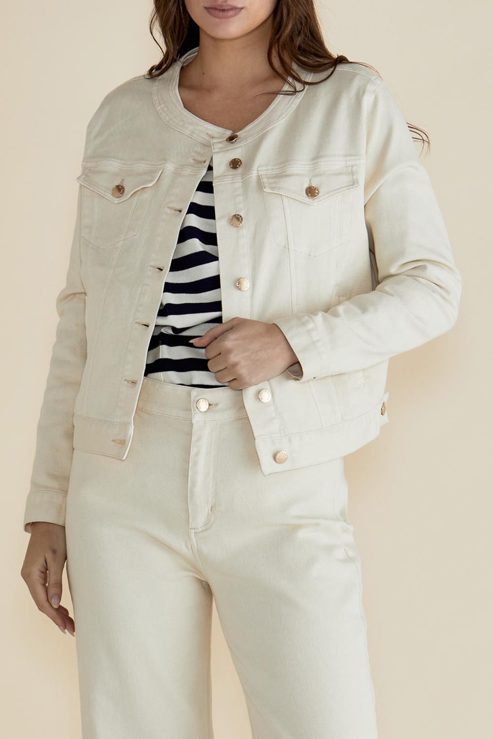 A model wearing the Cindy Collarless Denim Jacket in colour Offwhite (White), from the front, cropped image