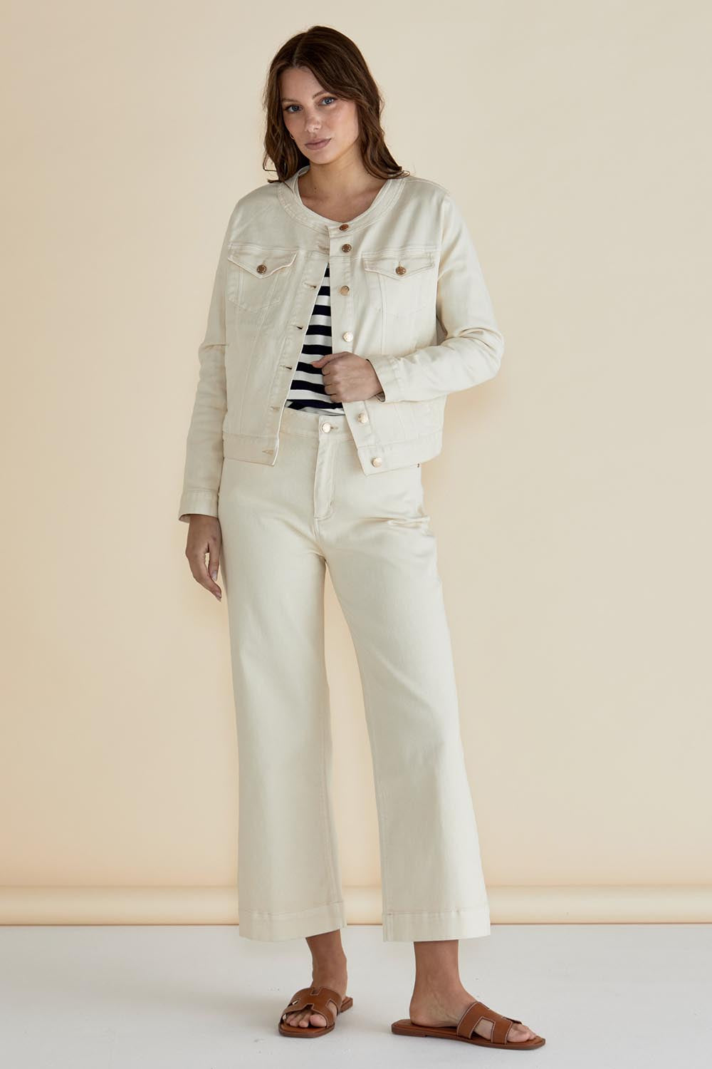 A model wearing the Cindy Collarless Denim Jacket in colour Offwhite (White), from the front, showing the whole outfit