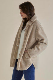 A model wearing the Teddy Jacket in colour Latte, from the front, cropped image