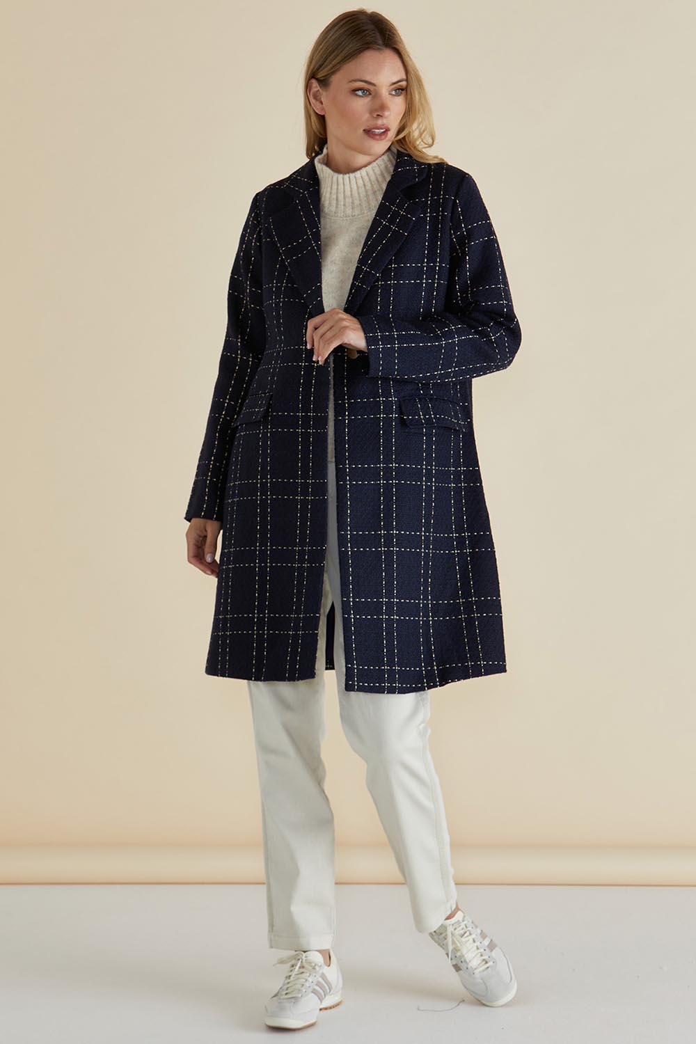 A model wearing the Genevieve Coat in colour Navycheck (Blue), from the front, showing the whole outfit