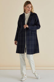 A model wearing the Genevieve Coat in colour Navycheck (Blue), from the front, showing the whole outfit