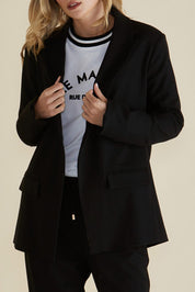 A model wearing the Portland Blazer in colour Black (Black), from the front, cropped image