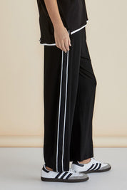 A model wearing the Evelyn Wide Leg Jogger in colour Black (Black), from the front, cropped image