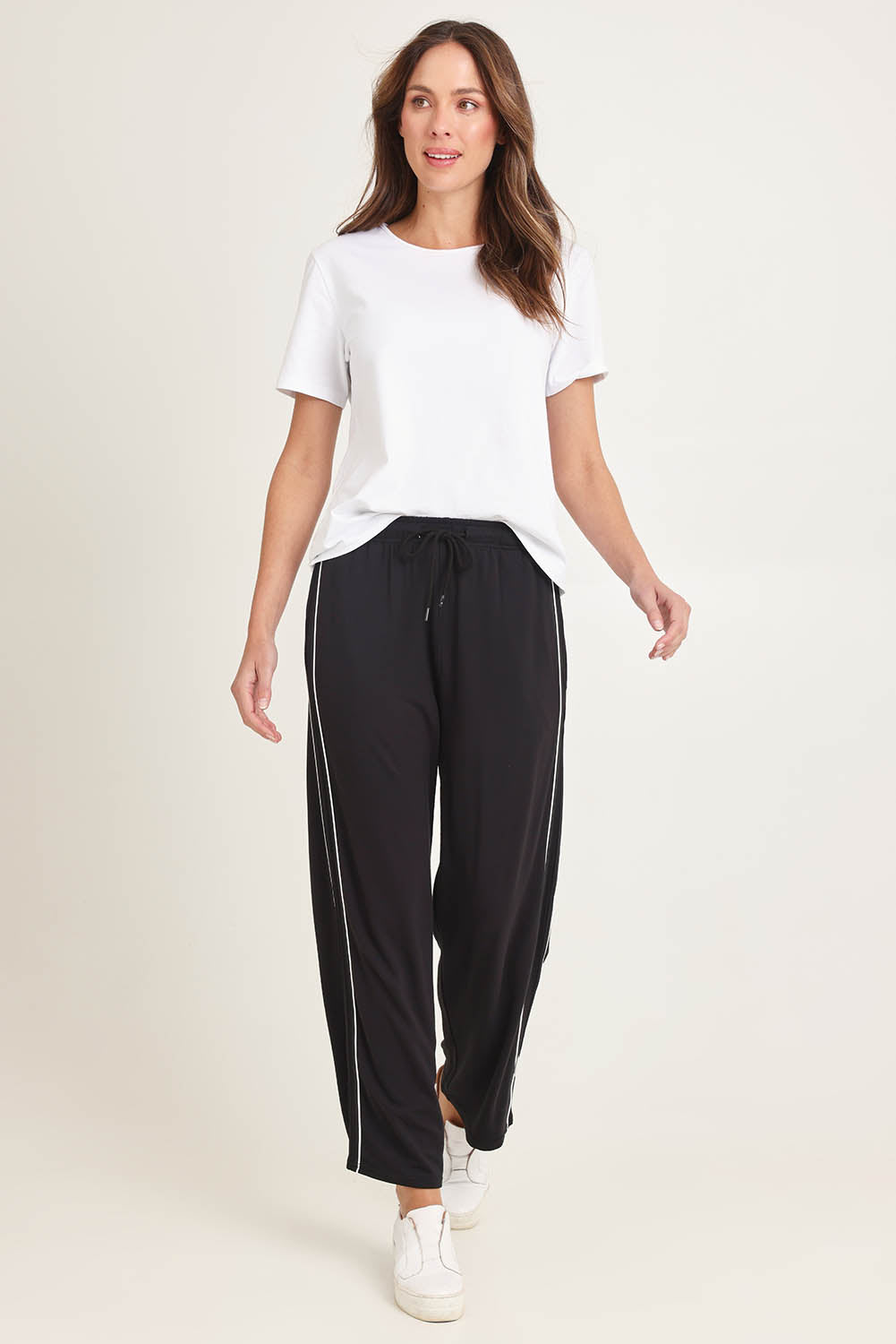 Model Madeline wearing size 10 of the Evelyn Wide Leg Jogger in colour Black (Black), from the front, showing the whole outfit