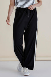 A model wearing the Evelyn Wide Leg Jogger in colour Blacktrim (Black), from the front, cropped image
