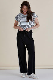A model wearing the Evelyn Wide Leg Jogger in colour Blacktrim (Black), from the front, showing the whole outfit