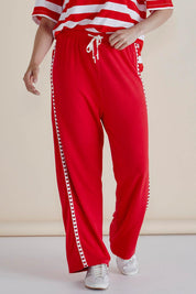 A model wearing the Evelyn Wide Leg Jogger in colour Redtrim (Red), from the front, cropped image