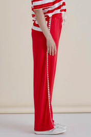 A model wearing the Evelyn Wide Leg Jogger in colour Redtrim (Red), from the front, cropped image