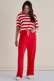 A model wearing the Evelyn Wide Leg Jogger in colour Redtrim (Red), from the front, showing the whole outfit