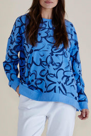 A model wearing the Palma Sweat in colour Bluefloral (Blue), from the front, cropped image