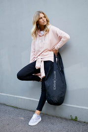 A model wearing the Oscar Hoodie in colour Blossom (Pink), from the front, showing the whole outfit