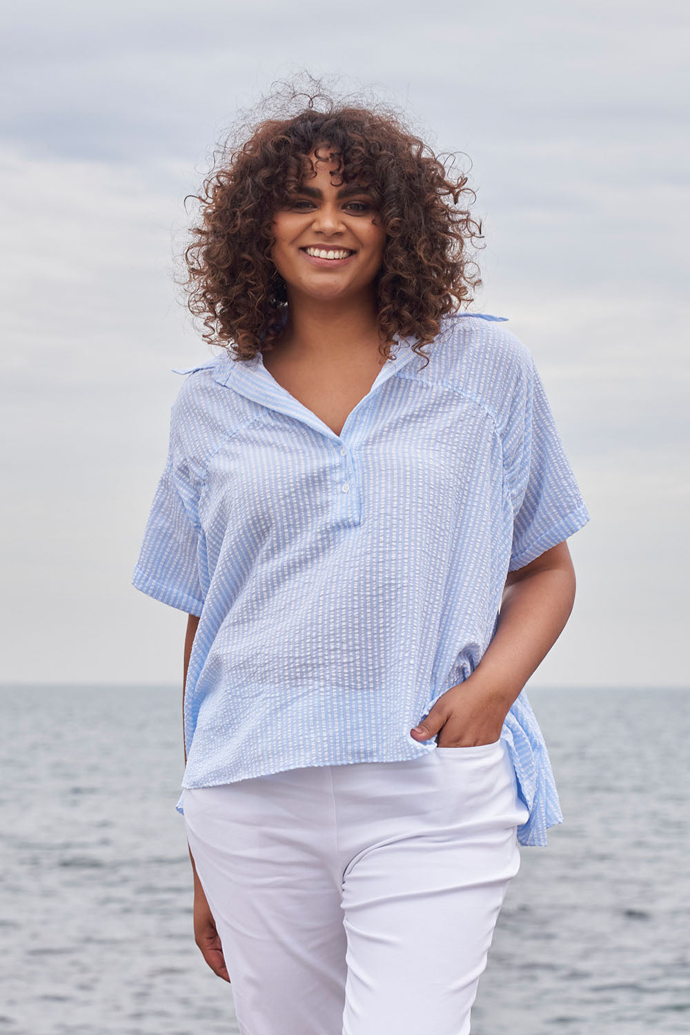 A model wearing the Sydney Smock Shirt in colour Blueseer (Blue), from the front, showing the whole outfit