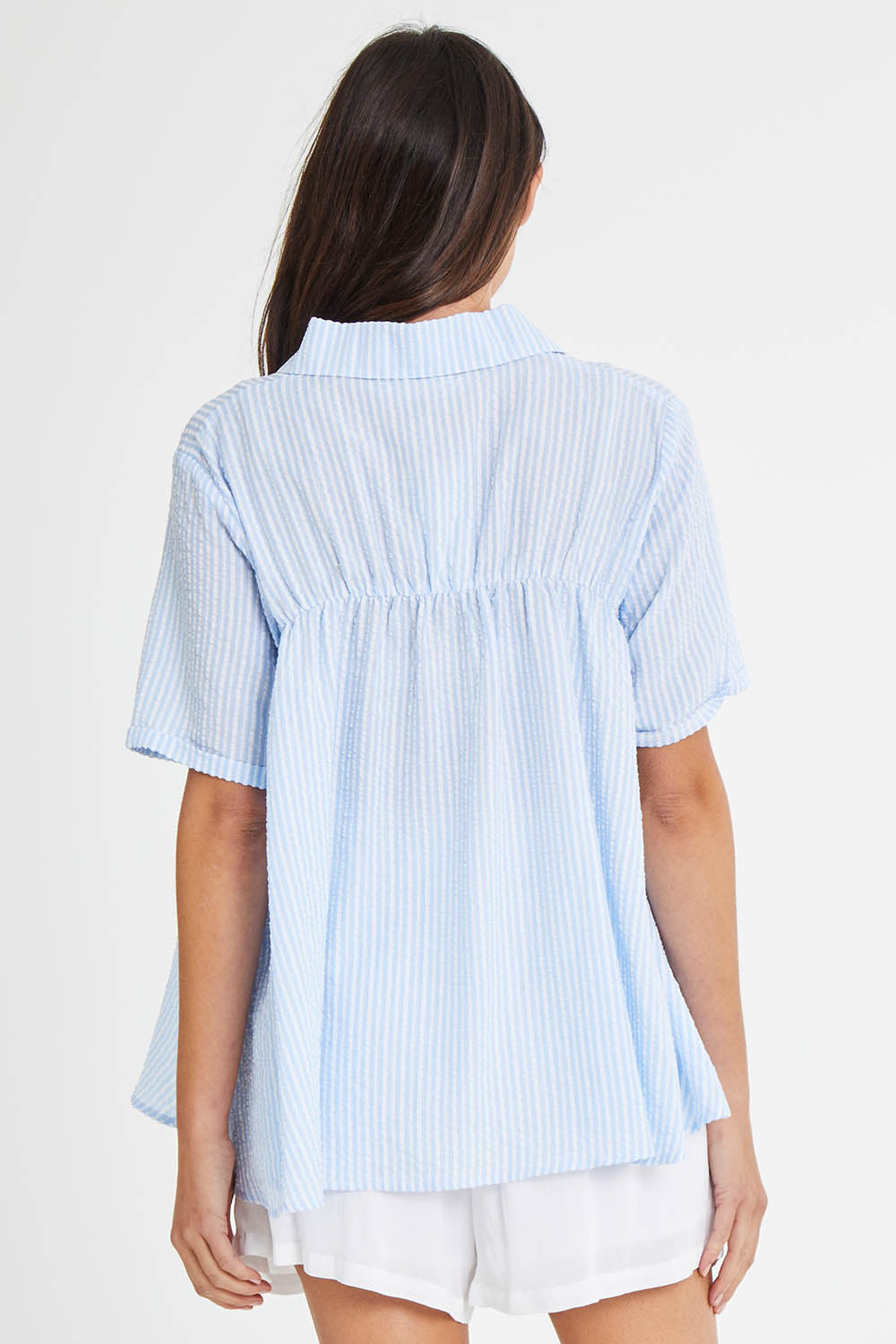 Model Madeline wearing size 10 of the Sydney Smock Shirt in colour Blueseer (Blue), from the back