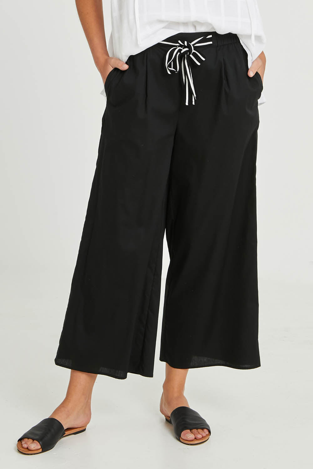 Model Madeline wearing size 10 of the Lulu Pant in colour Black (Black), from the front, cropped image