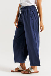A model wearing the Lulu Cotton Pant in colour Navy (Blue), from the front, cropped image