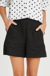 Model Madeline wearing size 10 of the Naples Linen Short in colour Black (Black), from the front, cropped image