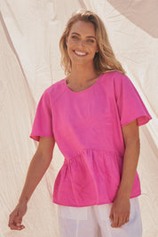 A model wearing the Cassandra Top in colour Azalea (Pink), from the front, showing the whole outfit