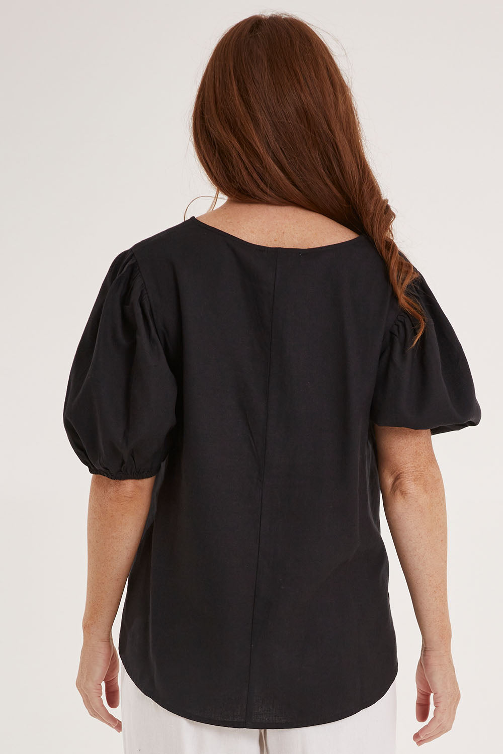 Model Sally wearing size 10 of the Alba Blouse in colour Coal (Black), from the back