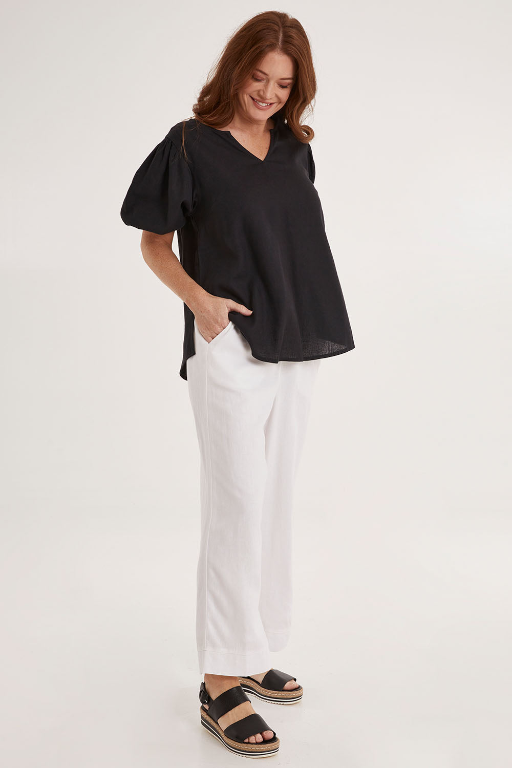 Model Sally wearing size 10 of the Alba Blouse in colour Coal (Black), from the front, showing the whole outfit