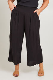 Model Poppy wearing size 16 of the Olympia Pant in colour Black (Black), from the front, cropped image