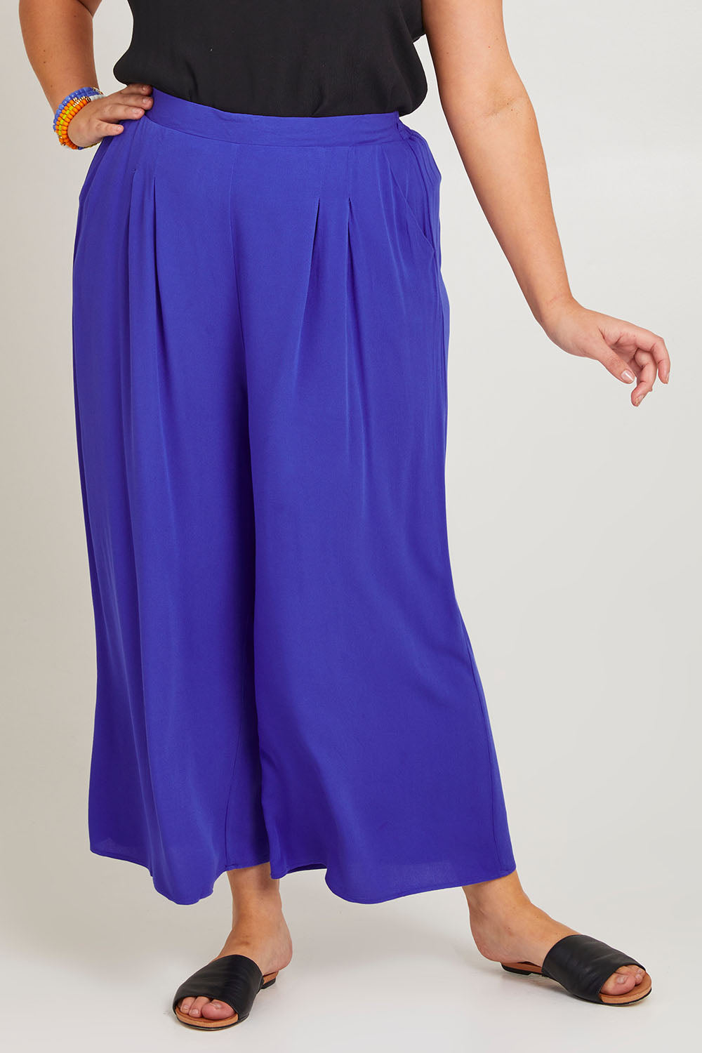 Model Poppy wearing size 16 of the Olympia Pant in colour Decoblue (Blue), from the front, cropped image