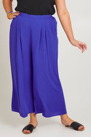 Model Poppy wearing size 16 of the Olympia Pant in colour Decoblue (Blue), from the front, cropped image