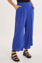 Model Sally wearing size 10 of the Olympia Pant in colour Decoblue (Blue), from the front, cropped image